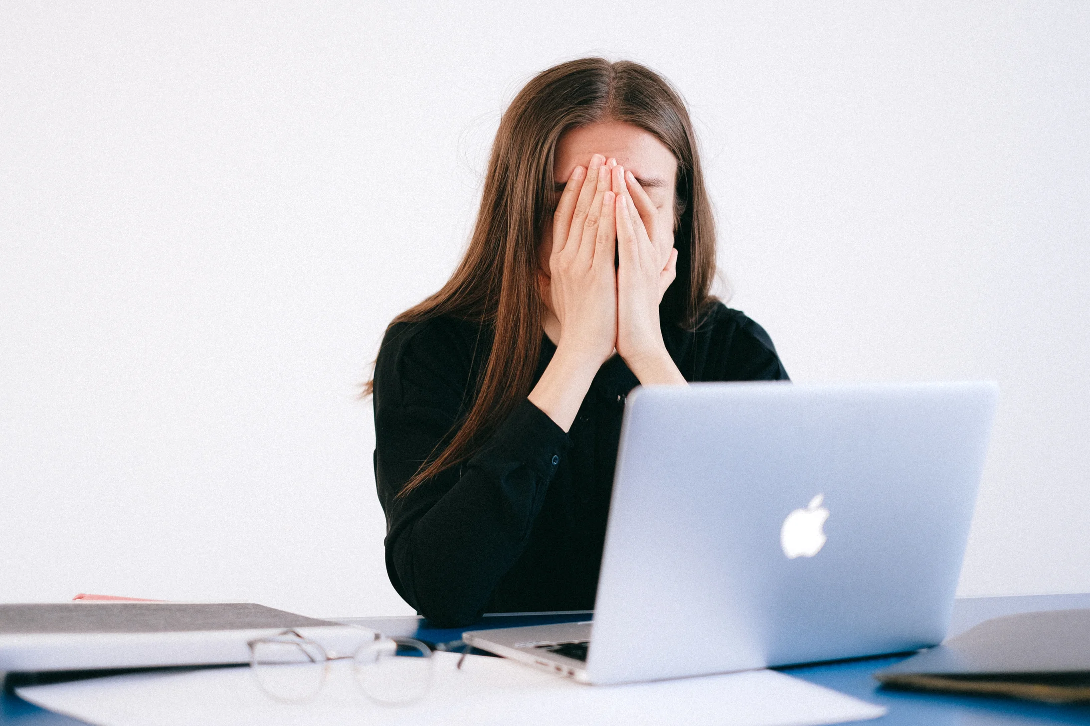 Woman with hands on her face in front of a laptop