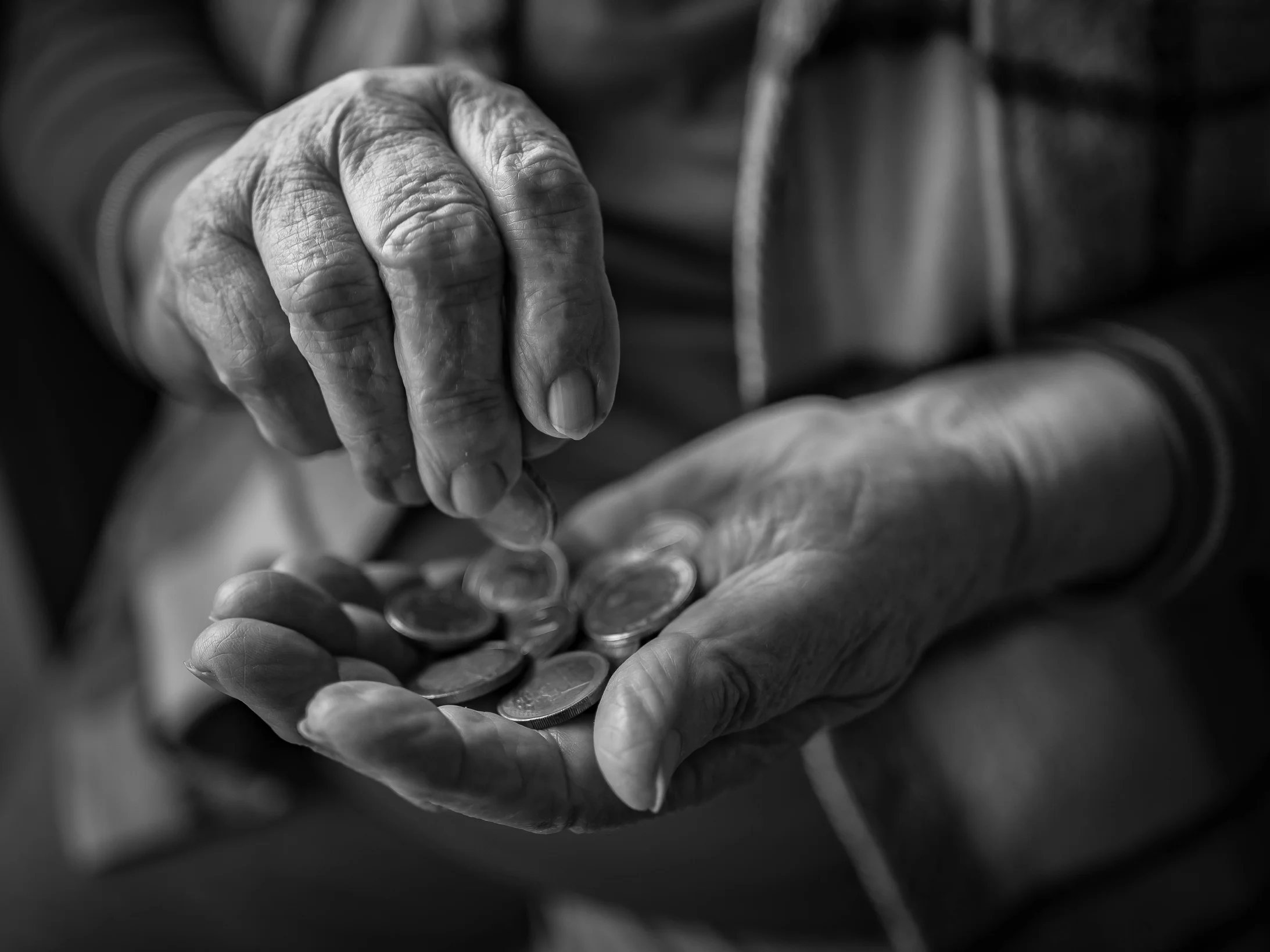 An old woman is holding a coin in her hand