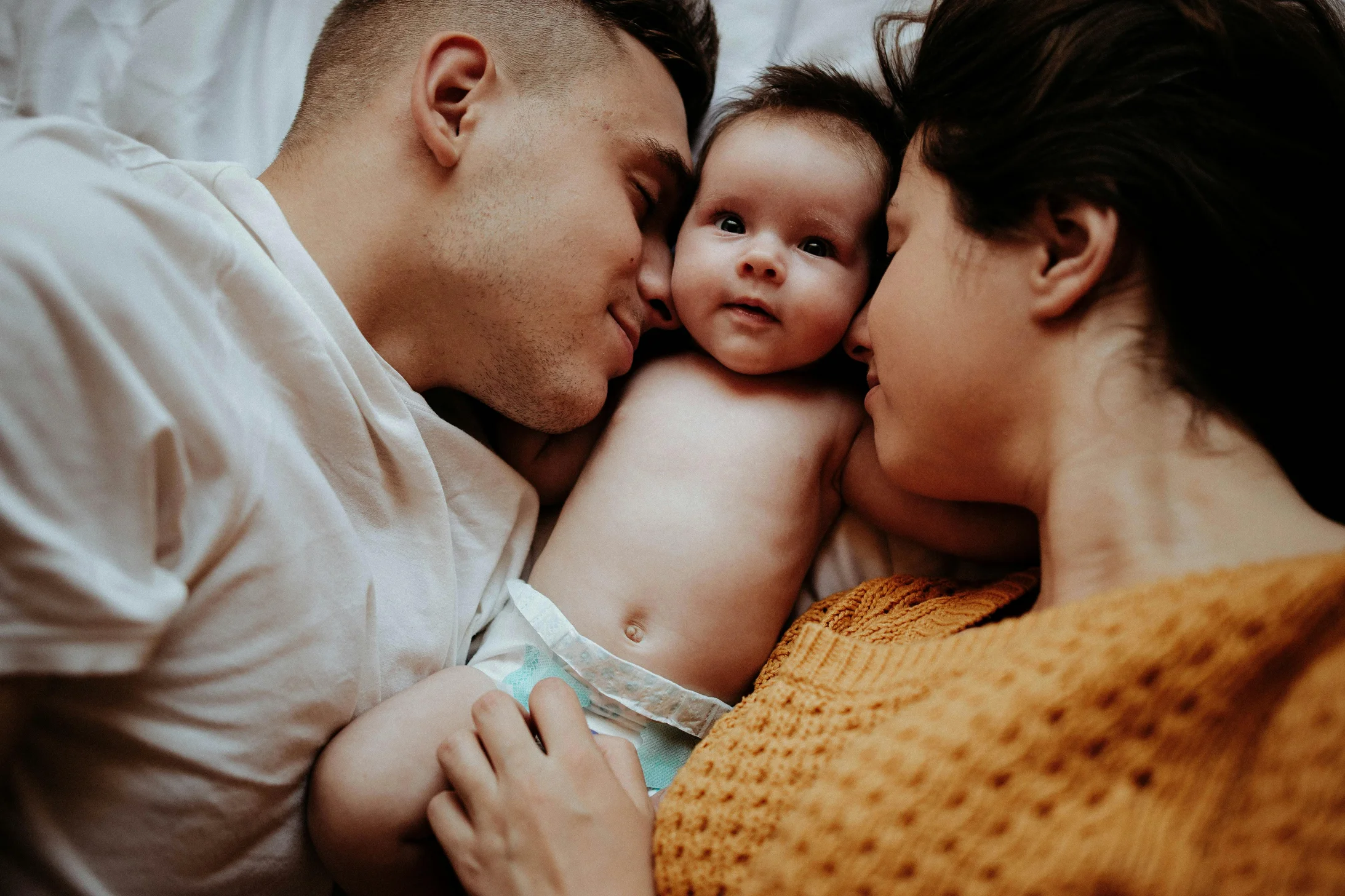 Parents lying on the bed with their newborn baby