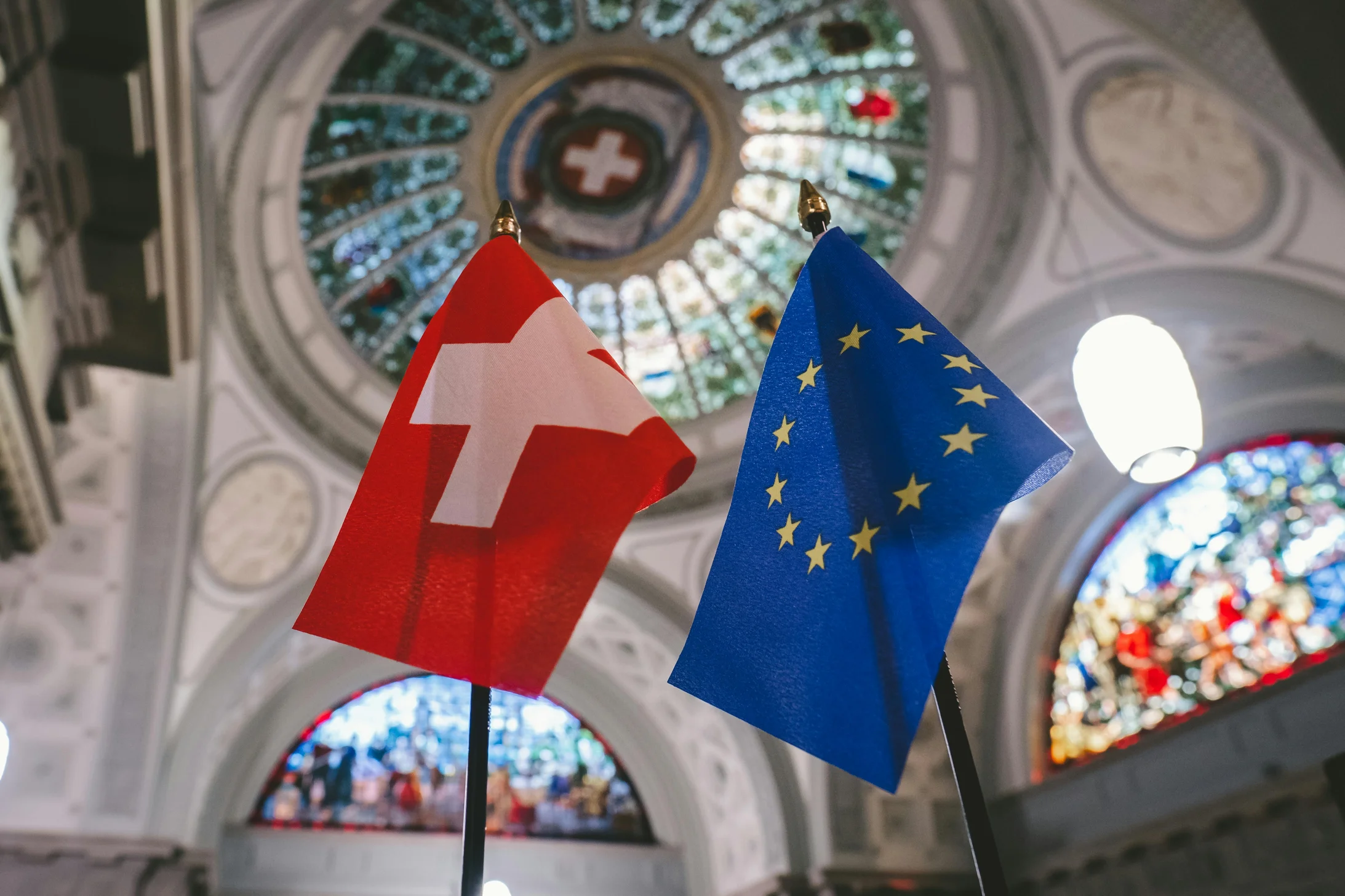 Switzerland and europian flags under a stained glass ceiling