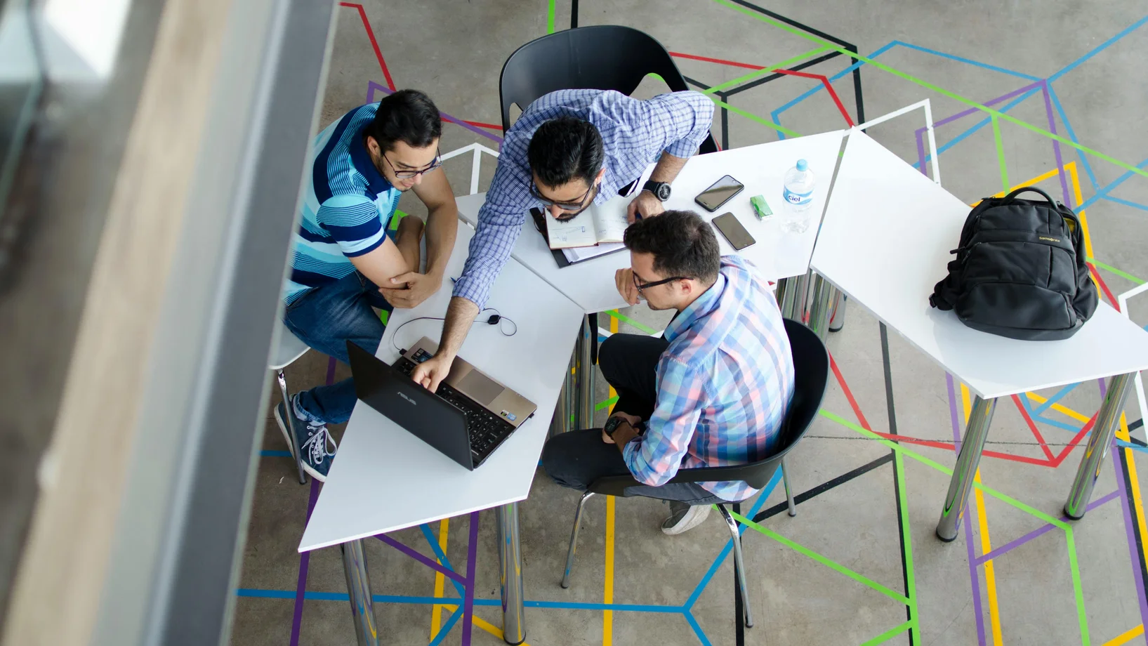 Top view photo of 3 men in front of laptop